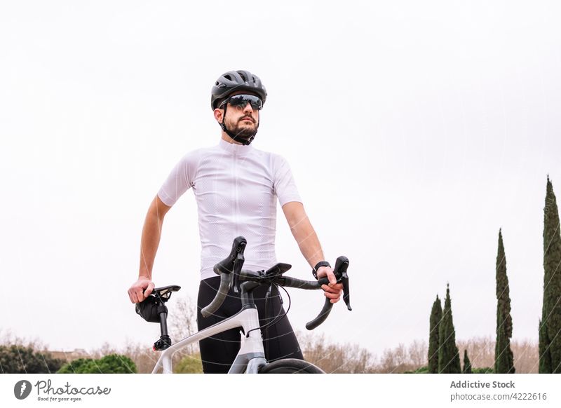 Bärtiger Biker mit Sonnenbrille und Fahrrad unter weißem Himmel Radfahrer Sport maskulin Macho viril selbstbewusst Stil Mann professionell Verkehr Fahrzeug