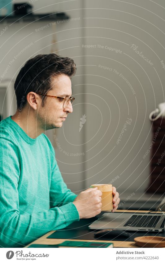 Fernangestellter mit Kaffee am Laptop zu Hause Mitarbeiter freiberuflich intelligent Arbeit Projekt Mann heimwärts benutzend Apparatur Gerät zuschauend Netbook