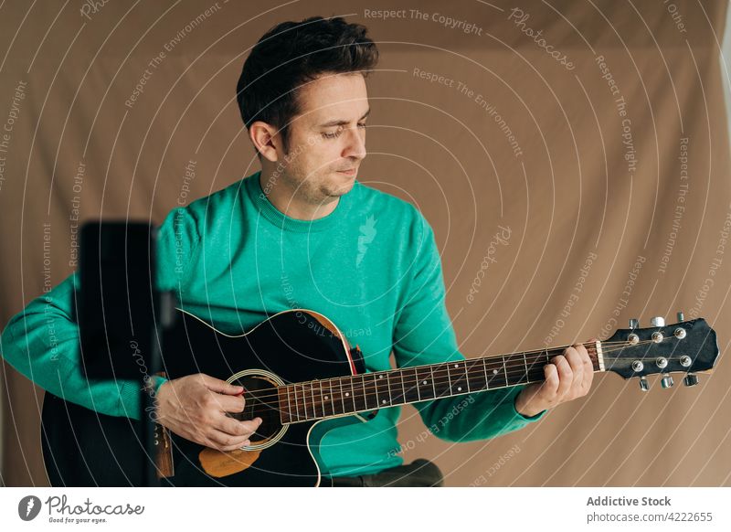 Musiker mit Gitarre, der mit seinem Smartphone ein Video aufnimmt Aufzeichnen vlog Mann Porträt benutzend Apparatur Gerät Funktelefon Plektrum Musical
