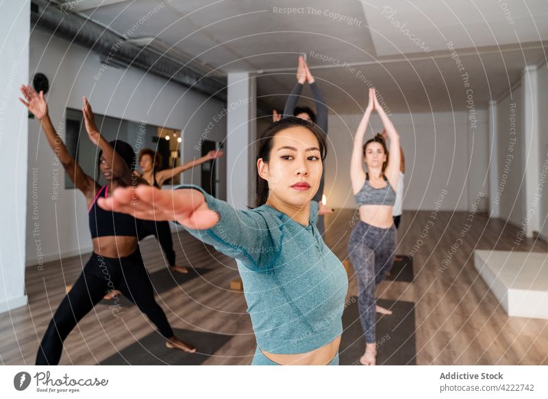 Asiatische Frau beim Yoga in Kriegerpose während einer Gruppenstunde Klasse Menschen Atelier üben Achtsamkeit Menschengruppe Krieger-Pose Zusammensein