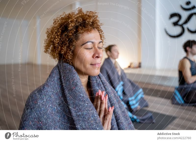 Ethnische Frau meditiert während einer Gruppen-Yogastunde meditieren Klasse Zusammensein Menschen Namaste Zen Achtsamkeit Menschengruppe multiethnisch