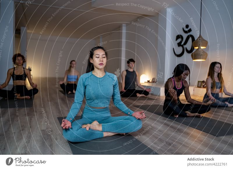 Friedliche multiethnische Menschen meditieren gemeinsam während einer Yogastunde Klasse Lektion Zusammensein asiatisch Achtsamkeit Zen Lotus-Pose Atelier