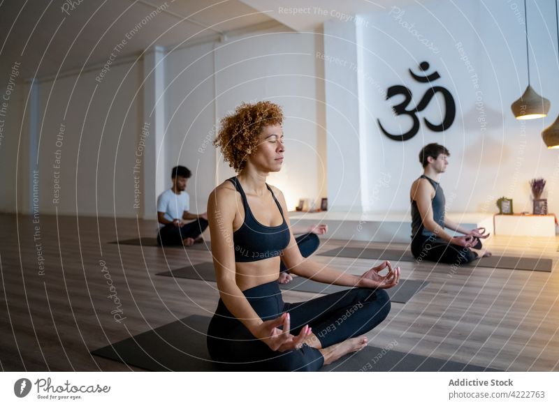 Friedliche multiethnische Menschen meditieren gemeinsam während einer Yogastunde Klasse Lektion Zusammensein Achtsamkeit Zen Lotus-Pose Atelier