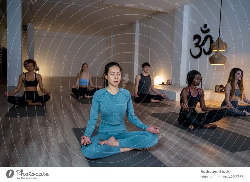 Friedliche multiethnische Menschen meditieren gemeinsam während einer Yogastunde Klasse Lektion Zusammensein asiatisch Achtsamkeit Zen Lotus-Pose Atelier