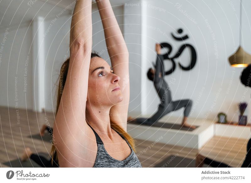 Junge Frau während einer Yoga-Gruppenstunde Klasse Lektion üben Krieger-Pose rassenübergreifend Gleichgewicht Asana virabhadrasana Wellness ausdehnen Waffen