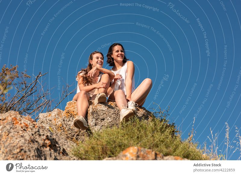 Fröhliche reisende Frauen sitzen auf einem Felsen in den Bergen Trekking Wanderung Berge u. Gebirge Hochland Hügel Pause Freund Zusammensein Natur Abenteuer