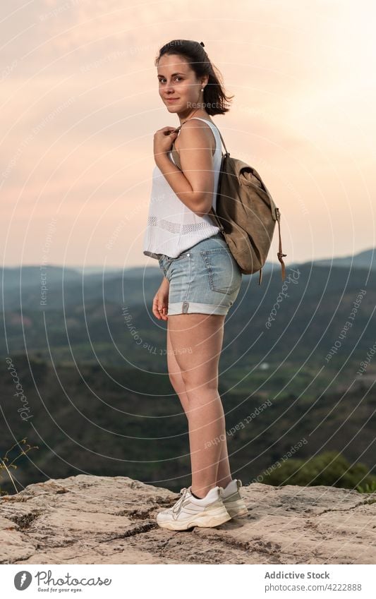 Lächelnde reisende Frau mit Rucksack im Hochland bei Sonnenuntergang Reisender Berge u. Gebirge Wanderer Natur Himmel Tourist Urlaub Abenteuer Freiheit Hügel