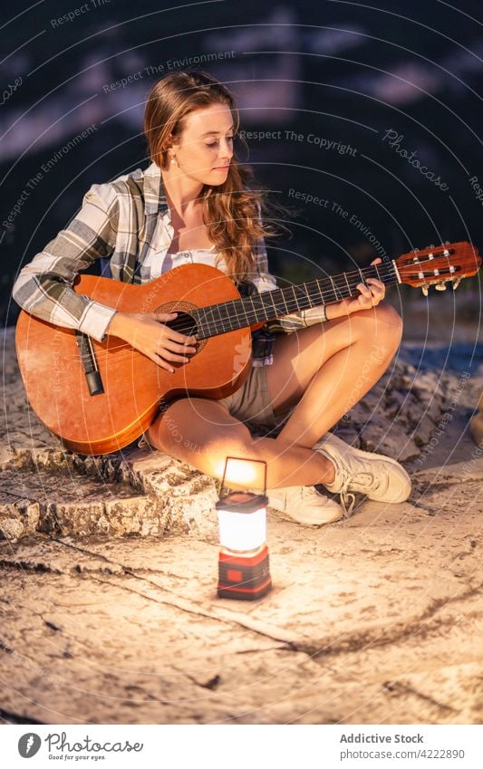 Reisende spielen Gitarre in den Bergen am Abend Reisender Frau Berge u. Gebirge reisen Musik Wanderer Spieler Laterne Licht glühen Natur sitzen Felsen genießen
