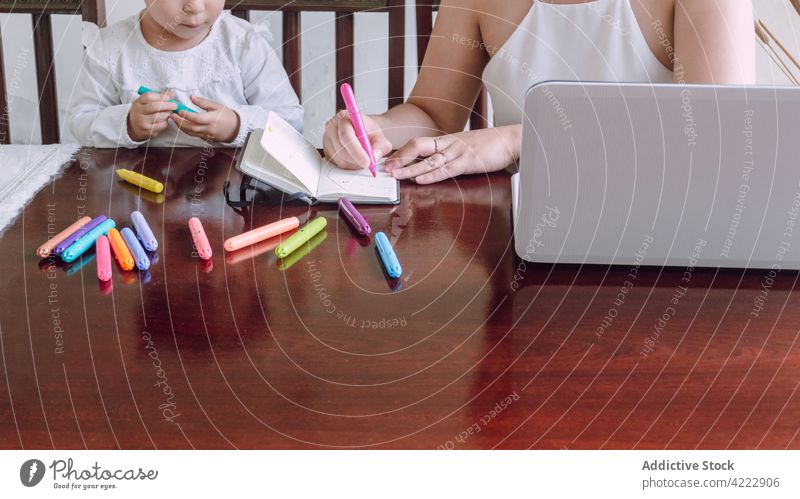 Crop Mutter und Kind zeichnen zusammen zu Hause Zusammensein Kinderbetreuung Markierung Filzstift heimwärts kreativ Bildung Notebook Tisch wenig Kindheit Hobby