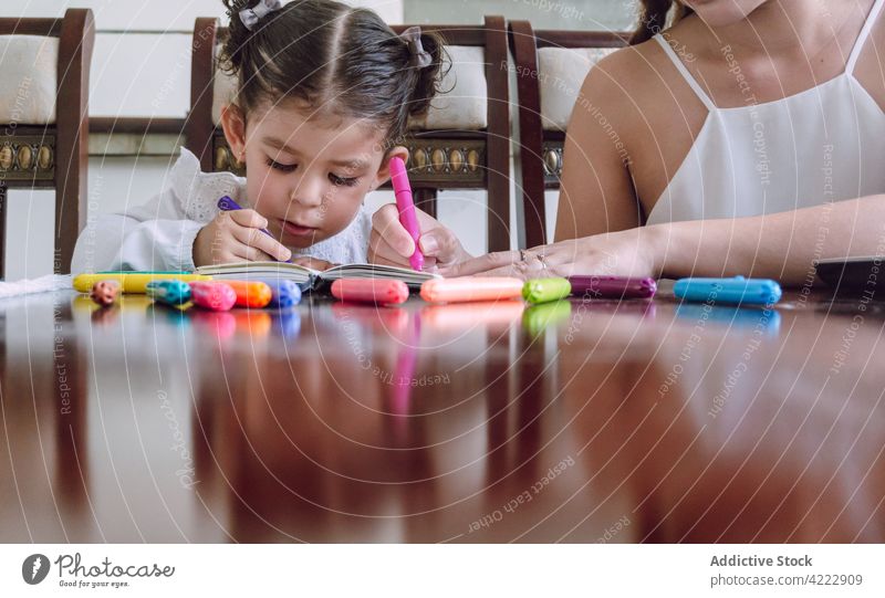 Crop Mutter und Kind zeichnen zusammen zu Hause Zusammensein Kinderbetreuung Markierung Filzstift heimwärts kreativ Bildung Notebook Tisch wenig Kindheit Hobby