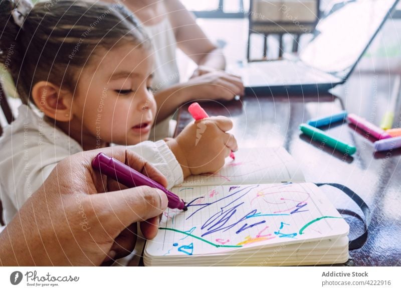 Crop Mutter Surfen Laptop und Kind Zeichnung zu Hause Zusammensein Kinderbetreuung Markierung zeichnen Filzstift heimwärts kreativ Bildung Notebook Tisch wenig