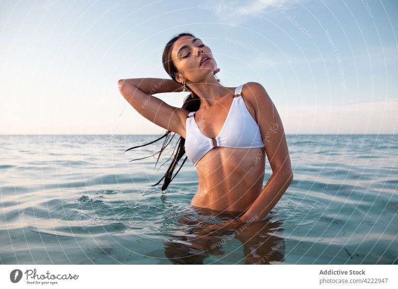 Sinnliches Modell im Badeanzug im gekräuselten Meer Haare berühren sinnlich Körper Hand hinter dem Kopf feminin Frau Porträt nasses Haar MEER Badebekleidung