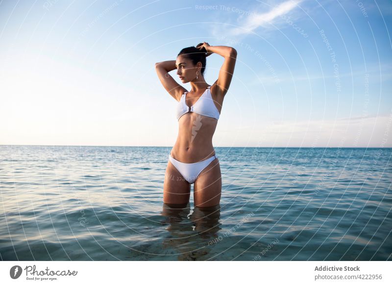 Modell im Badeanzug im Wasser am Strand MEER Körper Badebekleidung feminin selbstbewusst Meereslandschaft Frau Blauer Himmel attraktiv Natur wolkig sanft Sommer