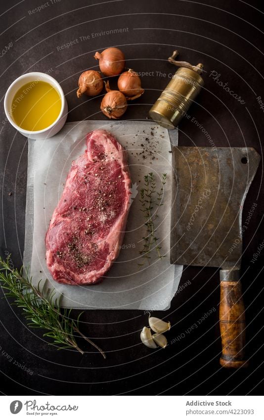 Rohes Rindersteak mit Gewürzen gegen Öl und frischen Zwiebeln Rindfleisch Steak Fleisch Bestandteil kulinarisch Rezept roh natürlich Hackmesser Erdöl oliv Beil