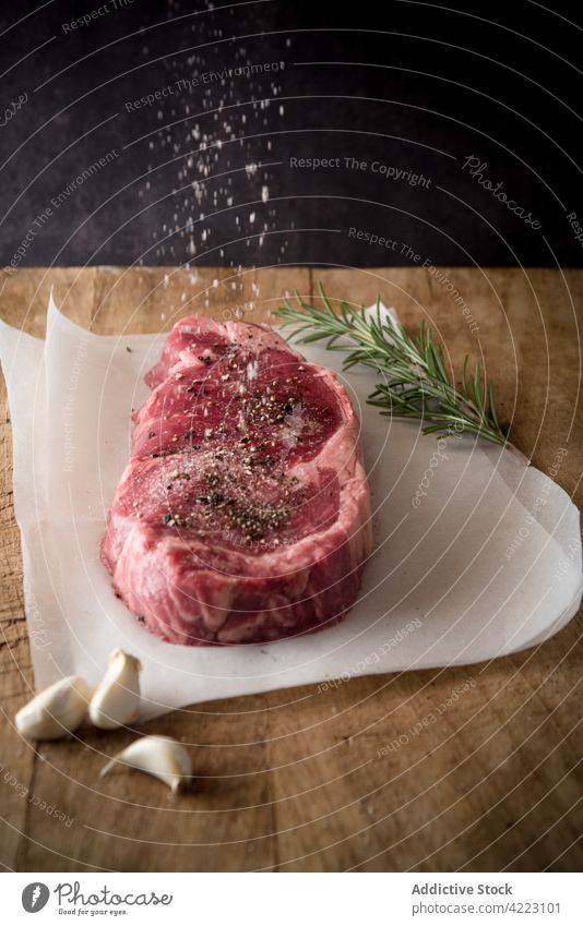 Ungekochtes Fleischsteak mit Gewürzen auf Pergamentblättern Steak Rindfleisch Salz fließen Protein ungekocht natürlich roh kulinarisch Rezept Bewegung