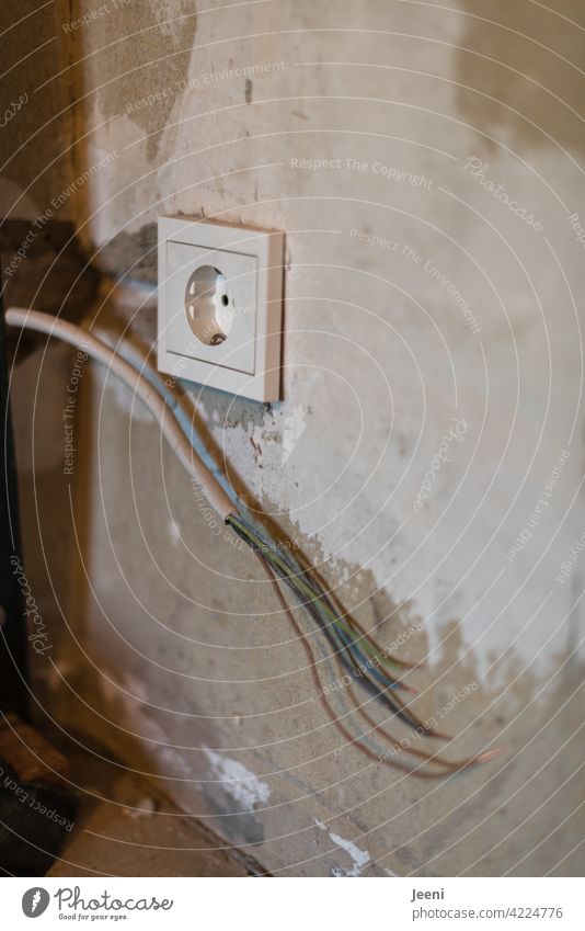 Stromsparmodus | ein Stromkabel hängt aus einer Zimmerwand im Rohbau, die Steckdose ist nicht am Kabel angeschlossen Kabelsalat Wand Umbauen umbau verputzen