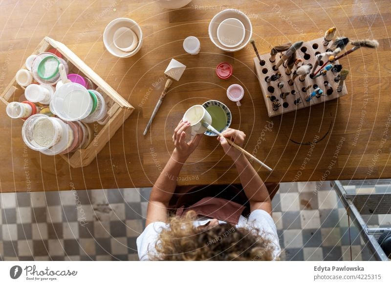 Kunsthandwerkerin bemalt eine Schale aus Ton im Kunstatelier Töpferwaren Künstler Keramik Arbeit arbeiten Menschen Frau jung Erwachsener lässig attraktiv Glück