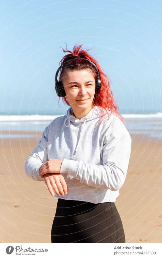 Sportlerin mit Headset am sandigen Meeresufer Athlet Kopfhörer nachdenken Gesunder Lebensstil Wellness Vitalität Frau Porträt benutzend Apparatur Gerät zuhören
