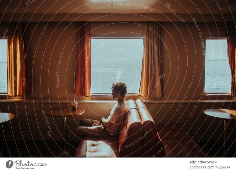 Junger Mann, der mit einer Fähre auf dem kräuselnden Meer fährt reisen Verkehr nachdenklich Reise Arbeitsweg MEER Schiff Passagier Boot Kreuzfahrt Öffentlich