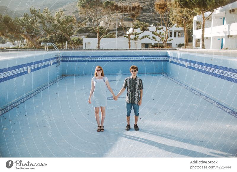 Junges Paar steht zusammen im Pool ohne Wasser leer Händchenhalten Windstille Resort Partnerschaft entwässert romantisch Zusammensein adamantas Milos