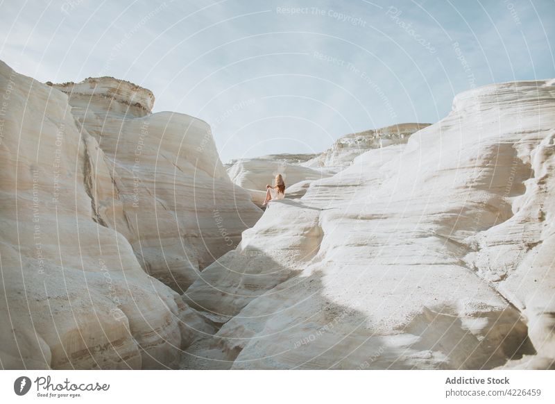Unerkennbare Frau sitzt an felsigen, kurvigen Formationen schlendern Geologie steinig Durchgang Natur Stein Weg sarakiniko Milos Griechenland eng Sonnenlicht