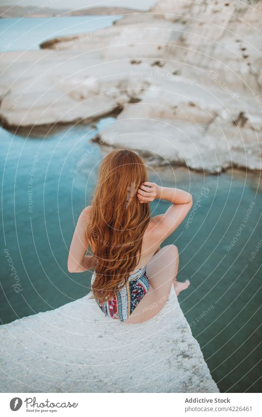 Anonyme Frau im Badeanzug auf felsiger Klippe ruhend Badebekleidung reisen Haare berühren Natur Resort Sonnenbad Felsen MEER sarakiniko Urlaub Bräune passen