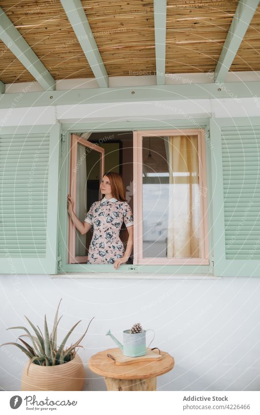 Verträumte Frau in der Nähe von modernen Häuschen stehend Cottage Fassade Haus verträumt lässig Vorschein jung Outfit Windstille emotionslos Sonnenkleid Sommer