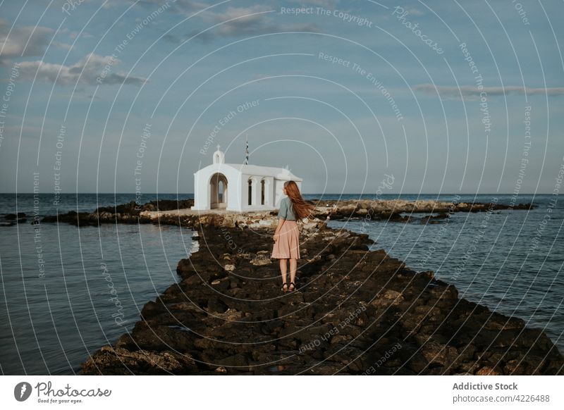 Unbekannte Frau steht in der Nähe einer weißen Kapelle auf einer steinigen Insel st. nikolaus-kapelle Kirche Inselchen reisen Natur anziehen Sightseeing