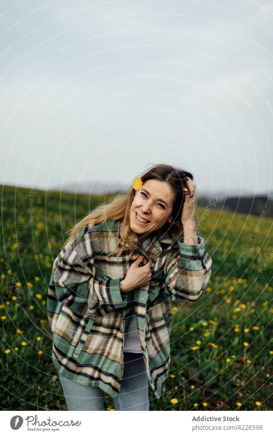 Fröhliche Frau, die ihr Haar in einem Feld auf dem Lande berührt Haare berühren heiter sorgenfrei genießen sanft Blume Landschaft Porträt Lächeln froh Inhalt