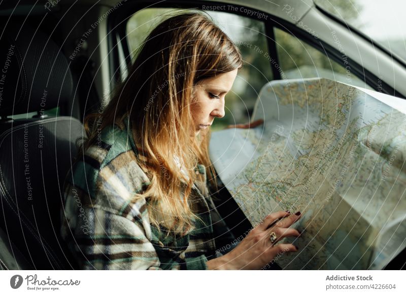 Fahrer schreibt während der Fahrt auf Papierkarte im Auto schreiben Landkarte Route Örtlichkeit Ausflugsziel Anleitung sich orientieren Frau PKW Schreibstift