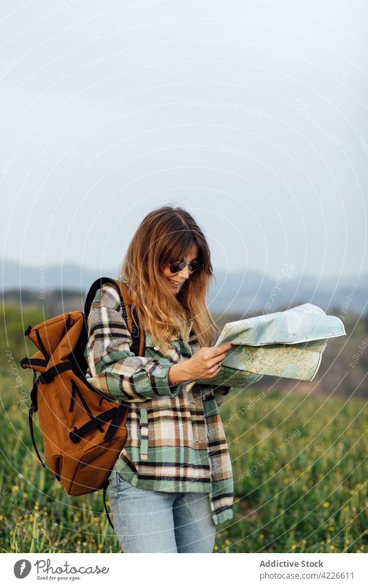 Wanderer mit Papierkarte in einem Feld auf dem Land Landkarte Reiseroute Ausflug Fernweh erkunden Lächeln Landschaft Frau Reisender feminin Tourist Himmel