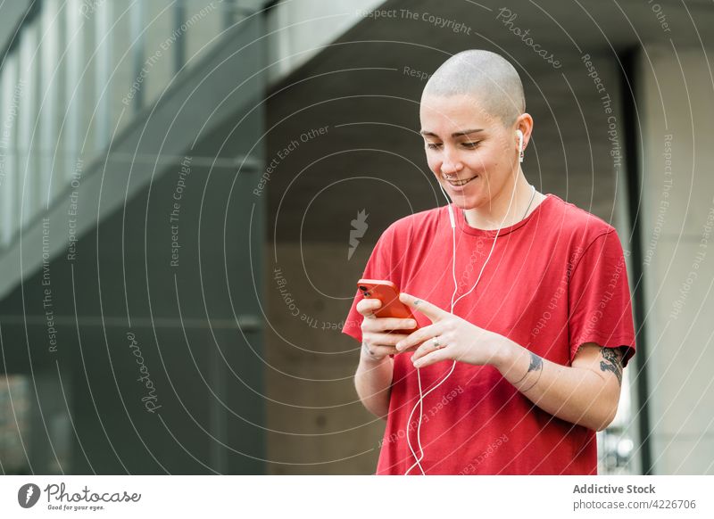 Lesbische Frau mit Smartphone und Tattoos auf einer Straße in der Stadt lesbisch Kopfhörer akzeptieren zuhören Glück Musik Großstadt Porträt benutzend Apparatur