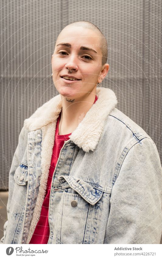 Queer mit Tattoo und Piercing auf grauem Hintergrund queer selbstbewusst Individualität Geschlecht akzeptieren Stil lässig Porträt Transgender androgyn Hochmut