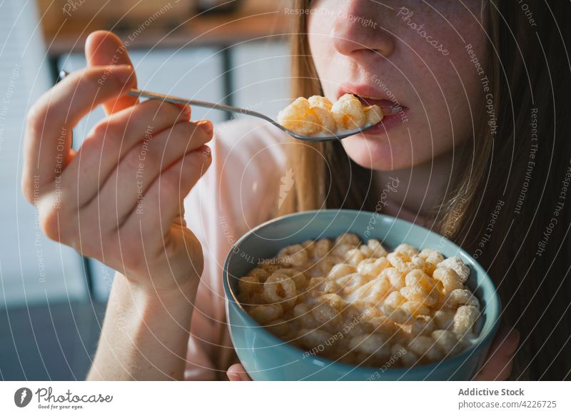 Crop-Frau isst leckeres Müsli zum Frühstück zu Hause essen Mais Ring süß Ernährung Porträt Küche heimwärts Portion Tisch heimisch Löffel Schalen & Schüsseln