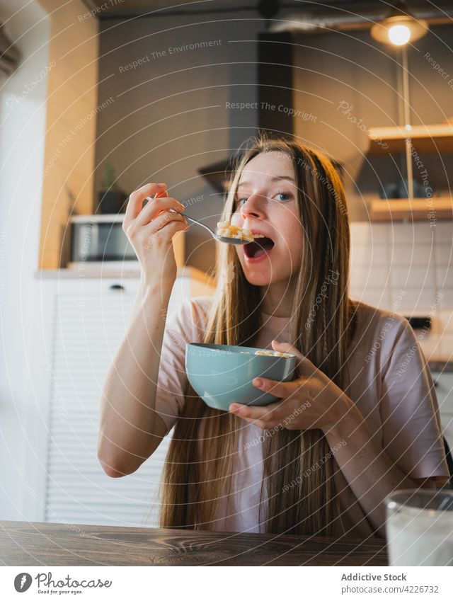 Frau isst leckeres Müsli zum Frühstück zu Hause essen Mais Ring süß Ernährung Mund geöffnet Porträt Küche heimwärts Portion Tisch heimisch Löffel