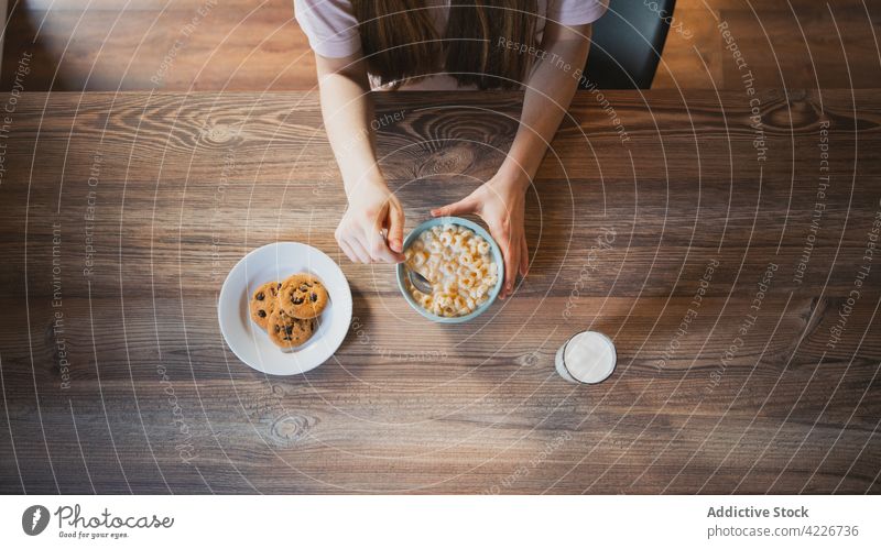 Crop-Frau mit leckerem Müsli zum Frühstück zu Hause Keks melken süß Nährstoff gebacken Tisch heimisch Glas Biskuit Haferflocken Schokolade Chip