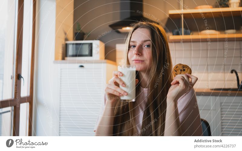Lächelnde Frau mit leckerem Haferkeks zu Hause Keks Leckerbissen Schokolade Chip süß gebacken Frühstück heimwärts heiter Küche Inhalt froh Wittern Getränk