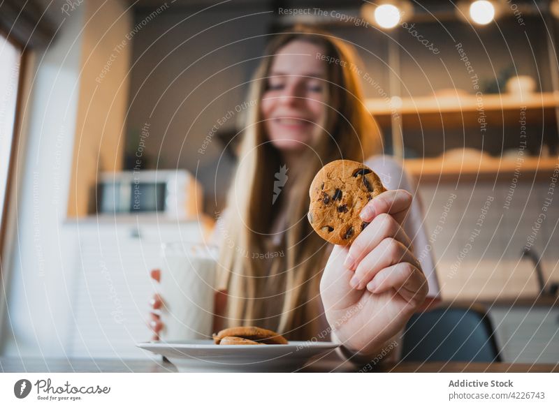 Lächelnde Frau mit leckerem Haferkeks zu Hause Keks Leckerbissen Schokolade Chip süß gebacken Frühstück heimwärts heiter Küche Inhalt froh Wittern Getränk