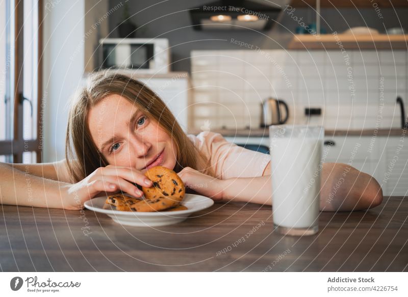 Frau mit leckeren Haferkeksen und Milch am Küchentisch Keks melken Frühstück süß Leckerbissen genießen Nährstoff Porträt Biskuit Haus trinken charmant heimwärts