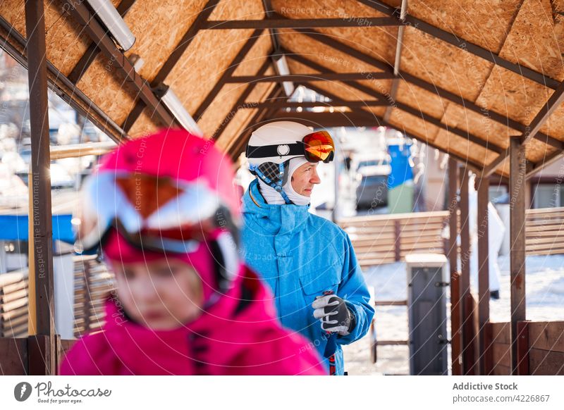 Glücklicher Vater in Helm und warmer Aktivkleidung im Skigebiet Mann heiter Aktivität warme Kleidung Sportkleidung Schutzhelm Schutzbrille Hobby Lächeln sonnig