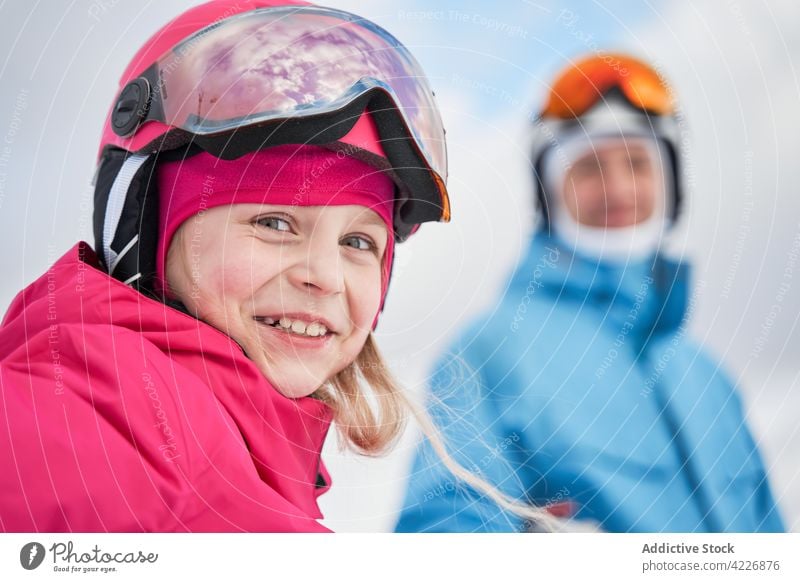 Glückliches Mädchen mit Skihelm in der Nähe der Eltern in der Natur stehend Sportkleidung Schutzhelm verschneite Vater Training Vitalität Zahnfarbenes Lächeln