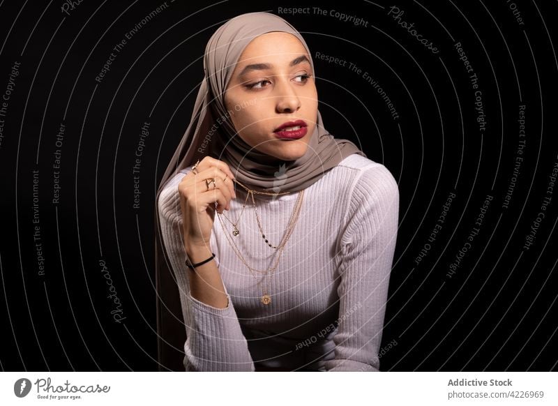 Stilvolle muslimische Frau lehnt auf einem Stuhl Kopftuch modisch selbstbewusst Vorschein Outfit Kopfschmuck Kleidungsstück Körperhaltung Kultur Model jung