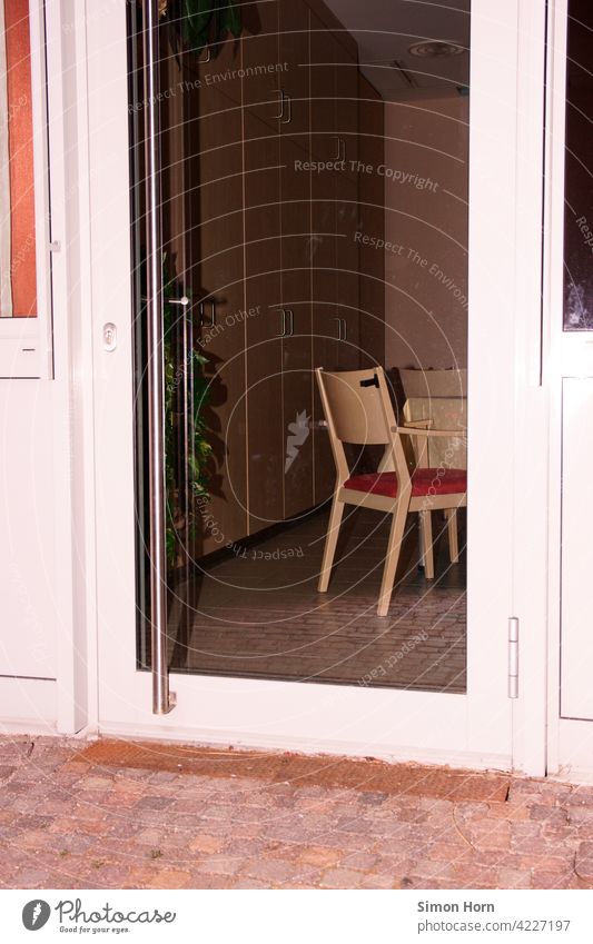 Blick durch eine Glastür auf einen menschenleeren Speisesaal Isolation Stuhl introvertiert Beobachtung Seniorenheim Teilhabe Gesellschaft Soziologie Ordnung