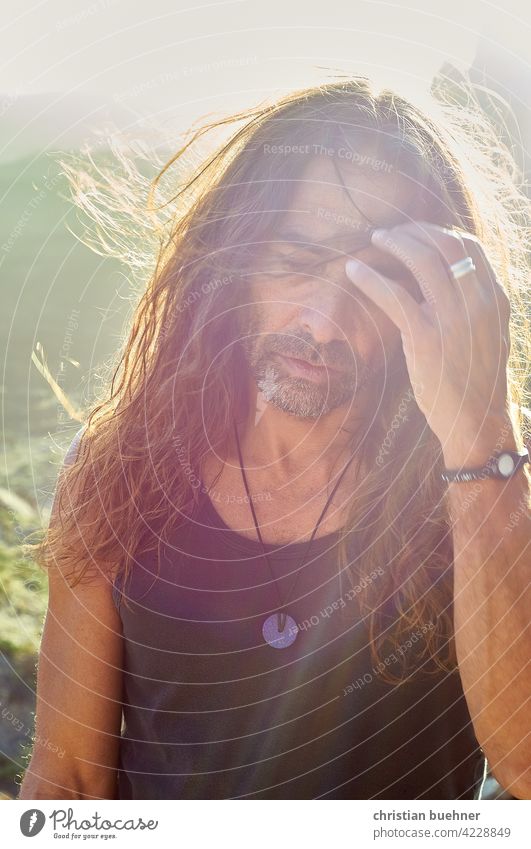 älterer hippie im sonnenuntergang mann portrait 50 jahre sommer lange haare alternativ junggeblieben urlaub nachdenklich gegenlicht meditation spirit natur berg