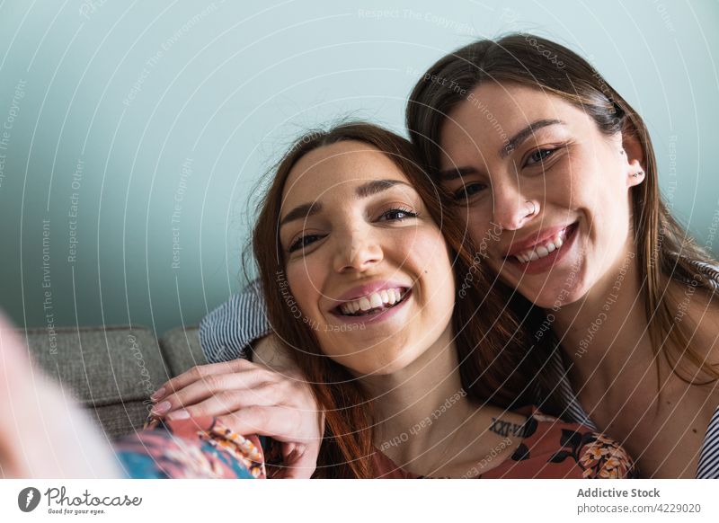 Lächelnde Frauen, die sich umarmen und ein Selfie mit ihrem Smartphone machen Zahnfarbenes Lächeln Freund Glück Zusammensein Umarmen Umarmung Selbstportrait