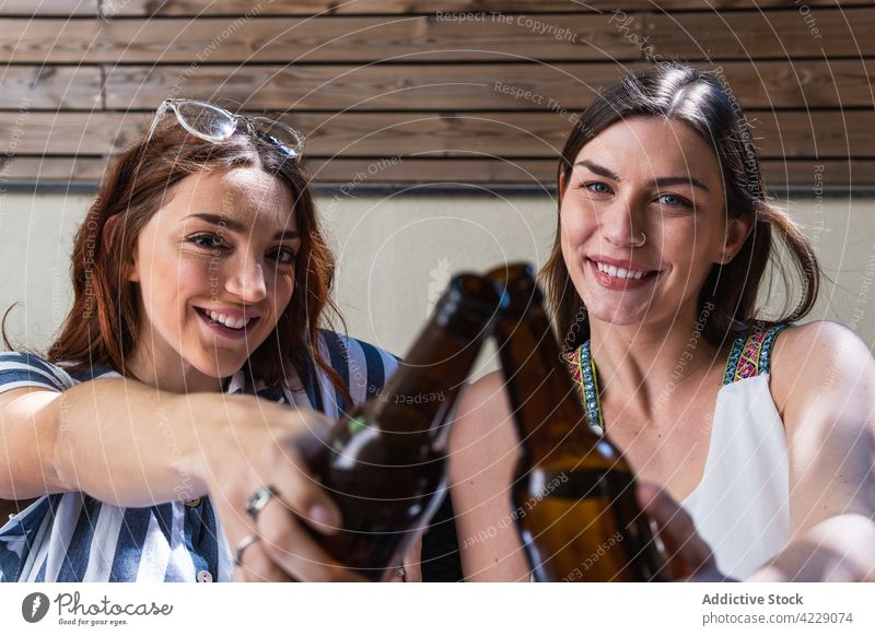Fröhliche Freundinnen mit Bier am Wochenende auf dem Sofa jubelt interagieren heiter Zeit verbringen Lifestyle Porträt Frauen Lächeln Kälte Alkohol trinken