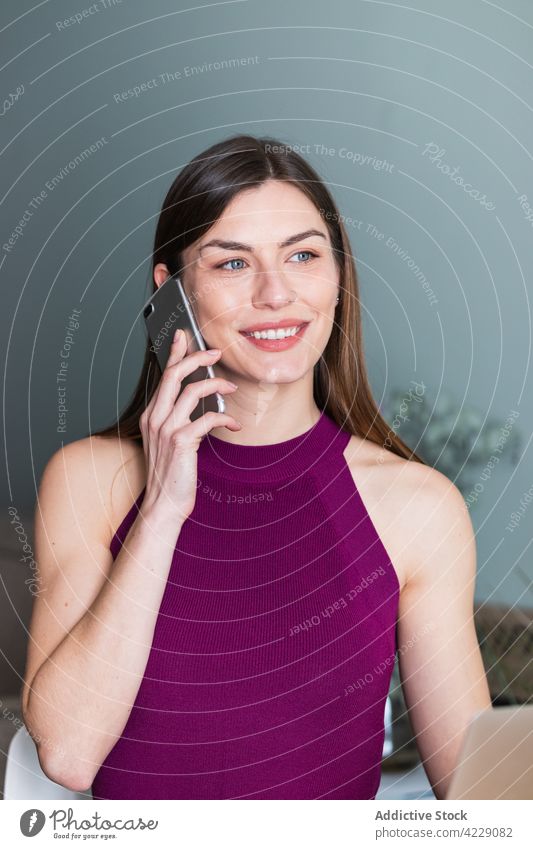 Lächelnde Frau, die zu Hause mit ihrem Smartphone spricht sprechen Zahnfarbenes Lächeln herzlich feminin charmant Porträt heimwärts benutzend Apparatur Gerät