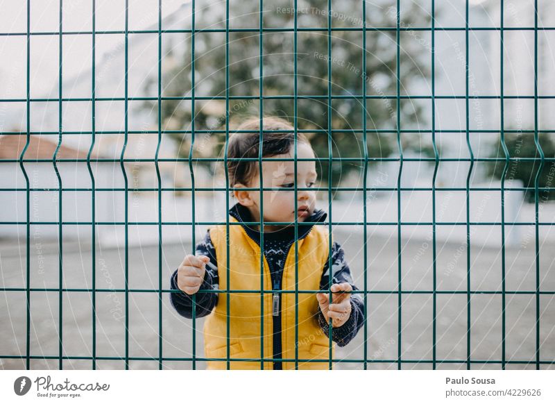 Kind hinter Zaun 1-3 Jahre Junge hinten Barriere maskulin Außenaufnahme Kleinkind Mensch Farbfoto Tag Porträt Schule Kindergarten Blick Kindheit
