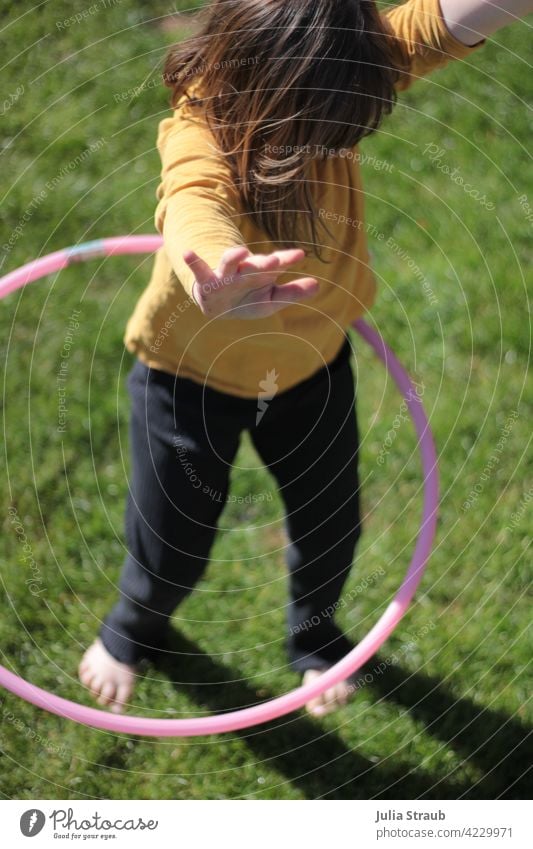 Hände hoch beim Hula hoop Mädchen Kindheit Kindergartenkind Spielen draußensein Hula Hoop Reifen hula hoo yeah dreht sich Kreis kreisend rund rosa gelb