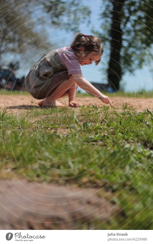 Mädchen zeichnet im Sand Spielen draußen sein Wiese Gras Barfuß Kleid T-Shirt Zopf Stock schreiben zeichnen malen deuten Sommer Frühling Sonne Sonnenschein